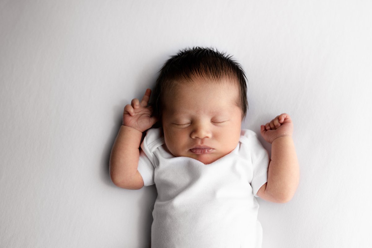 newborn baby boy on white blanket in white onesie newborn photographer mitchell sd studio