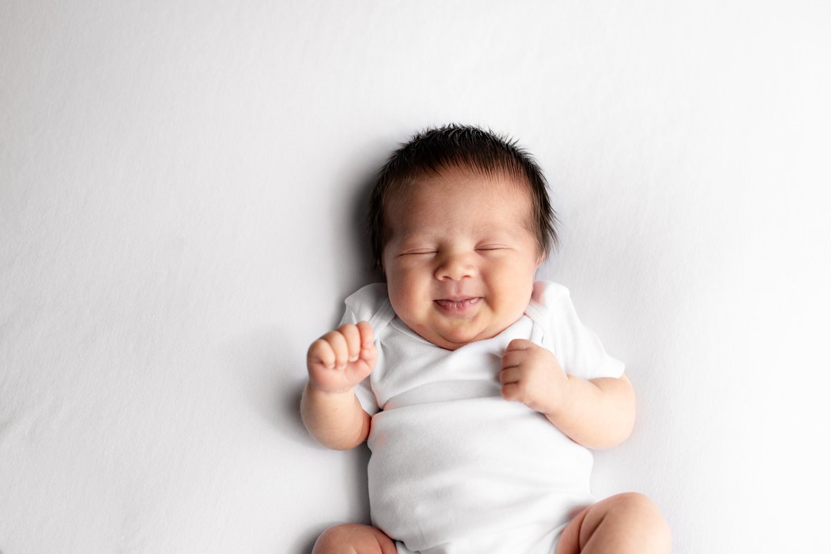 smiling newborn baby in white onesie