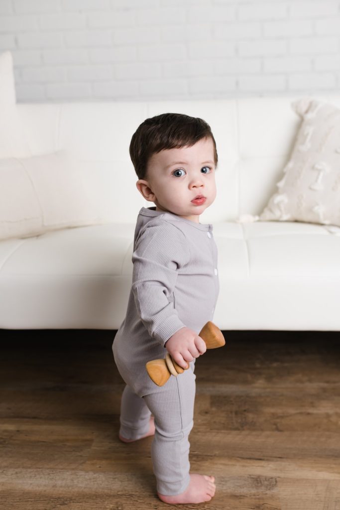 little boy standing against couch
