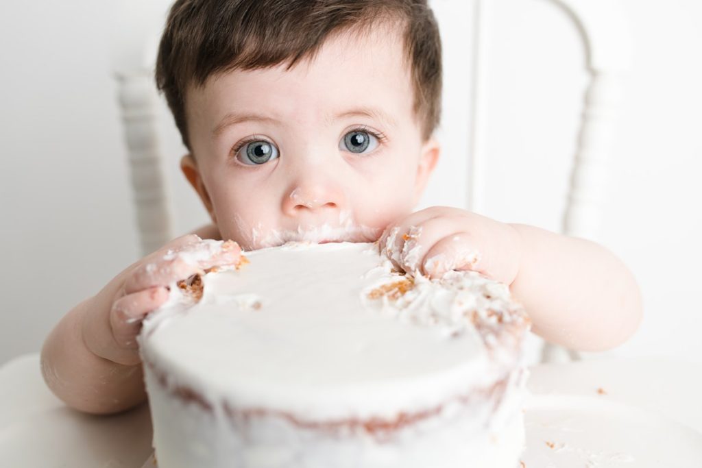 one year old eating white cake
