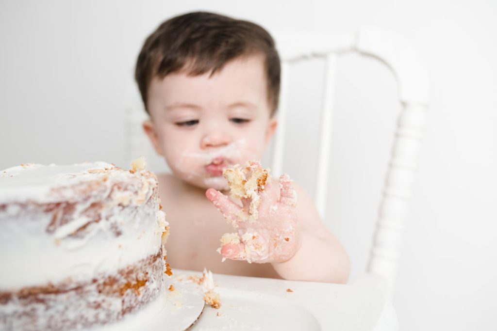 one year old playing with white cake